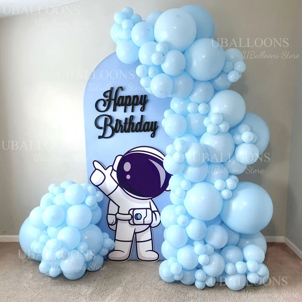 A large balloon arch featuring light blue balloons and a silver astronaut figure for a birthday party decoration.