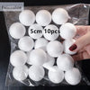 A hand holds a clear plastic bag filled with 10 white polystyrene foam balls for crafting.