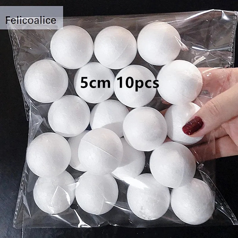A hand holds a clear plastic bag filled with 10 white polystyrene foam balls for crafting.