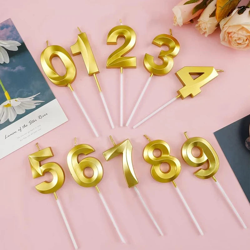 Gold acrylic number cake candles shaped like 1, 2, 3, 4, 5, 6, 7, 8, and 9 arranged on a pink background.