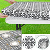 Black and white patterned elastic fitted rectangle tablecloth being held over a white table.