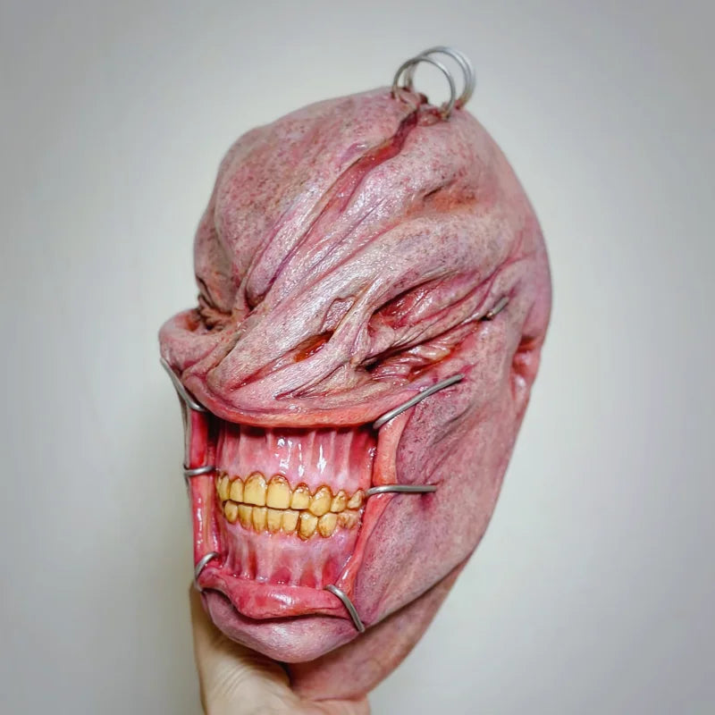 A realistic cute alien full-face latex mask with an open mouth showing teeth and facial wrinkles.