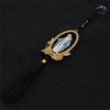 A wooden pendant ornament depicting Our Lady of Grace with a blue and white robe, suspended by a dark cord.