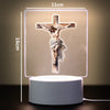 A 3D LED night light depicting a crucifixion scene on a cross, illuminated with a soft glow.