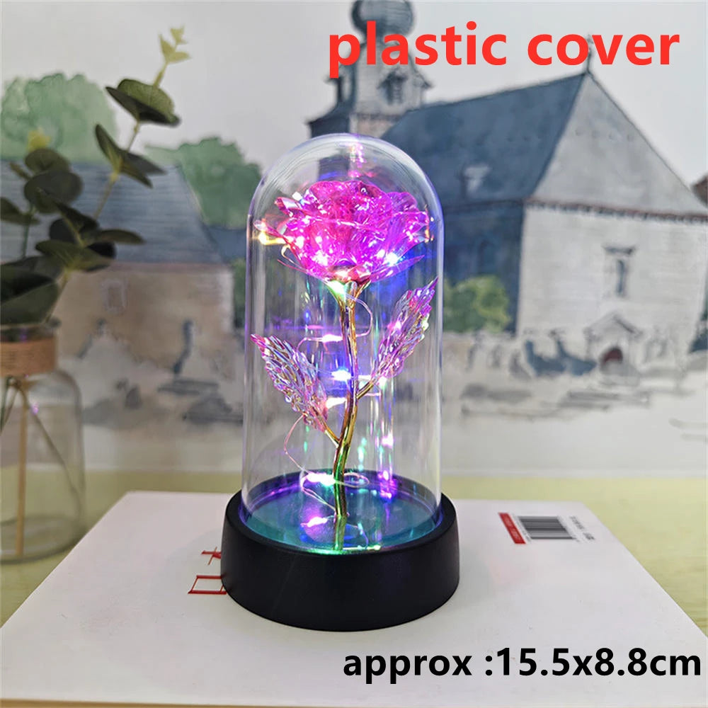 A glass dome containing a pink LED galaxy rose artificial flower displayed on a black base.