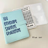 A light blue leather binder for a 100 envelope savings challenge with numbered pockets and a clear plastic sleeve.