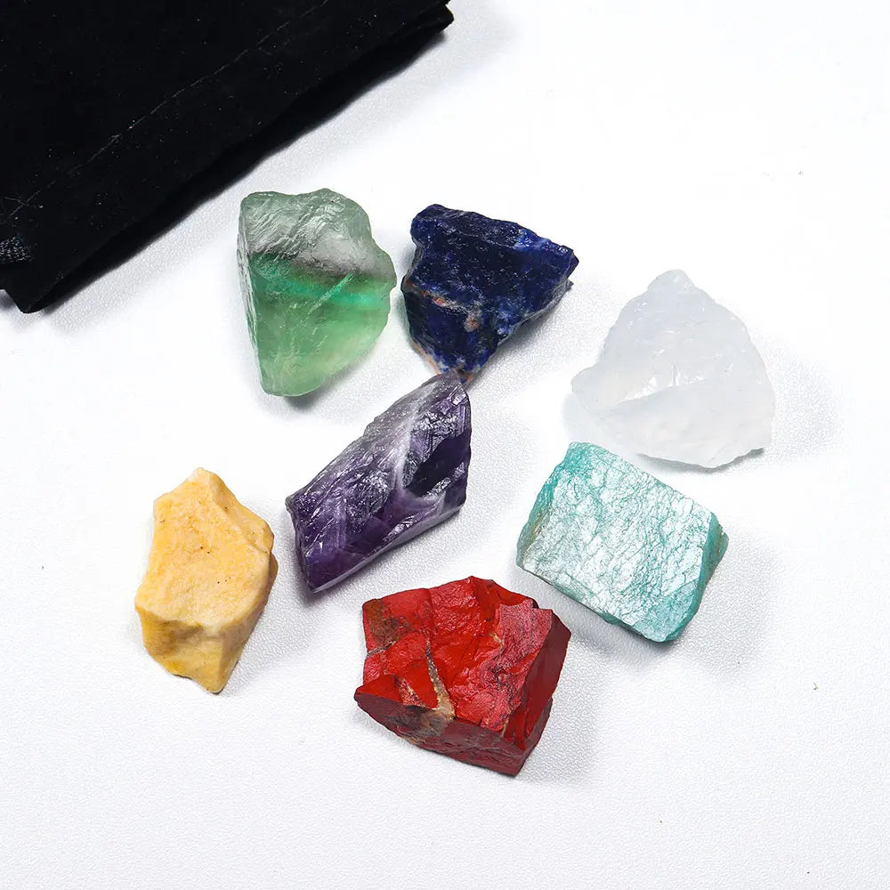 A collection of natural crystal healing stones in various shades of green, blue, purple, and clear quartz on a white backgrou