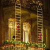A building facade decorated with vertical strings of warm white Christmas lights and Santa figures.