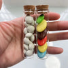 Mini glass bottles with cork stoppers filled with colorful beads and stones