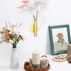 A modern wall-mounted flower vase with an elegant gold finish displaying white and pink blossoms.