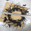 An artificial black branch bat wreath for Halloween door decor is laid out on brown paper next to a ruler.