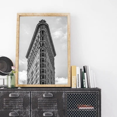 A framed black and white photograph of a tall, ornate building against a cloudy sky.