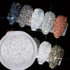 A collection of iridescent nail rhinestones in various glitter colors and sizes displayed on a white plastic tray.