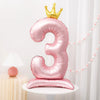 A pink foil balloon shaped like the number three with a gold crown on top