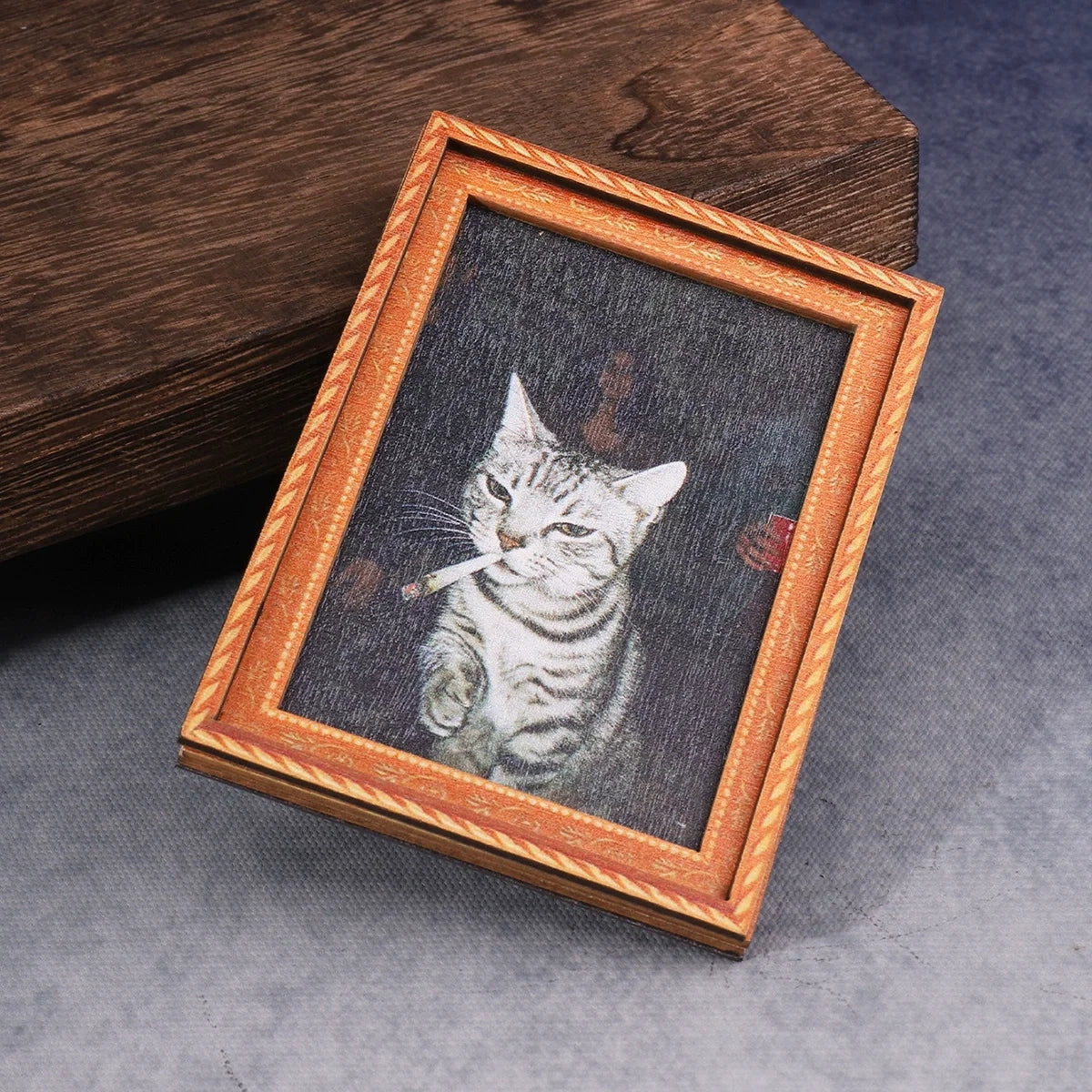 A framed print of a cat smoking a cigarette, displayed in a wooden frame.