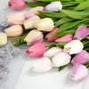 A bouquet of artificial tulips in shades of pink and white on a white background.