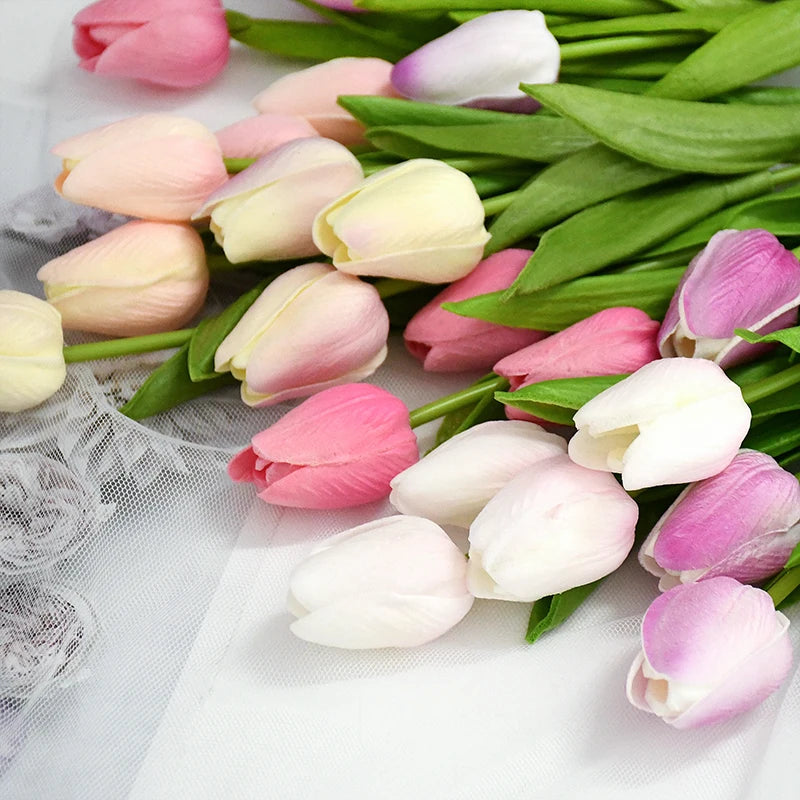 A bouquet of artificial tulips in shades of pink and white on a white background.