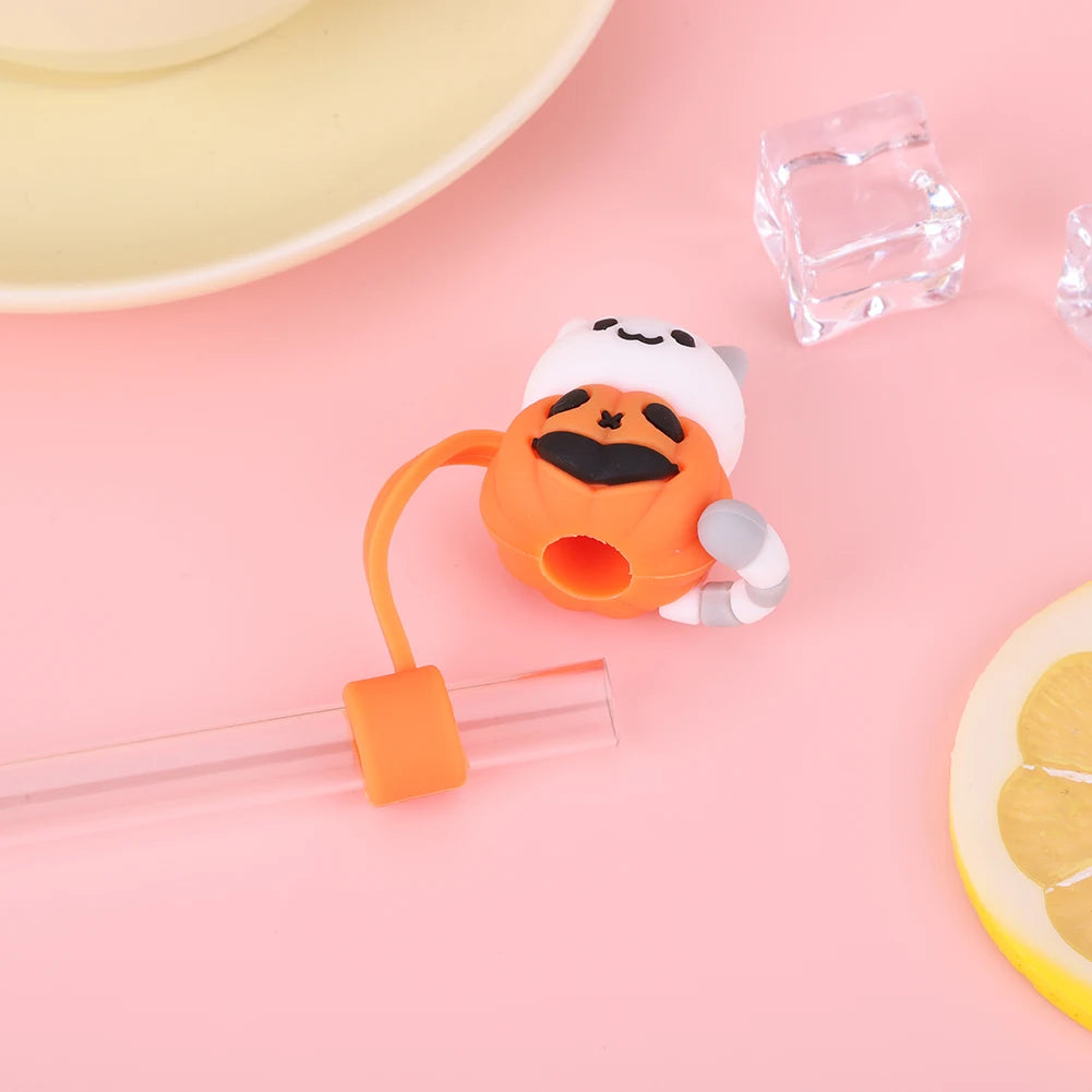 Orange silicone straw covers with white silicone lids and a clear glass cube on a pink background
