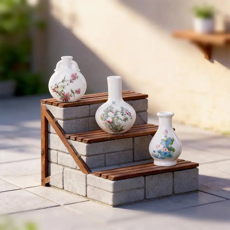 A set of eight white resin vases with floral patterns displayed on stacked wooden and stone blocks outdoors.
