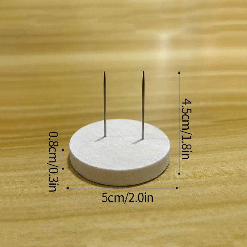 A white circular object with two thin metal pins is shown on a wooden surface, measuring 5cm in diameter and 4.5cm high.