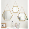 A hexagon decorative wall mirror with a gold frame hanging on a white wall.
