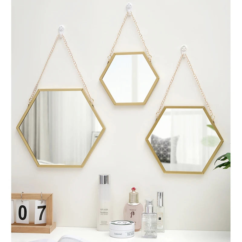 A hexagon decorative wall mirror with a gold frame hanging on a white wall.