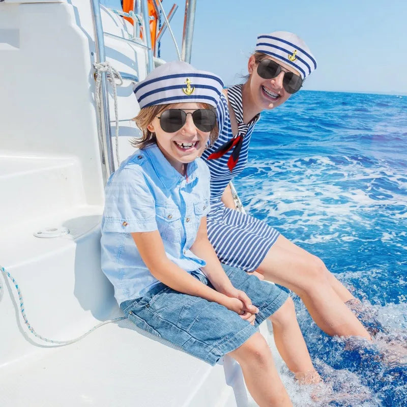 A smiling woman wearing sunglasses and a striped shirt is sitting on a boat railing with blue water in the background.