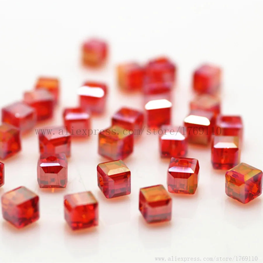 A pile of square cut red glass crystal beads for jewelry making scattered on a white surface.