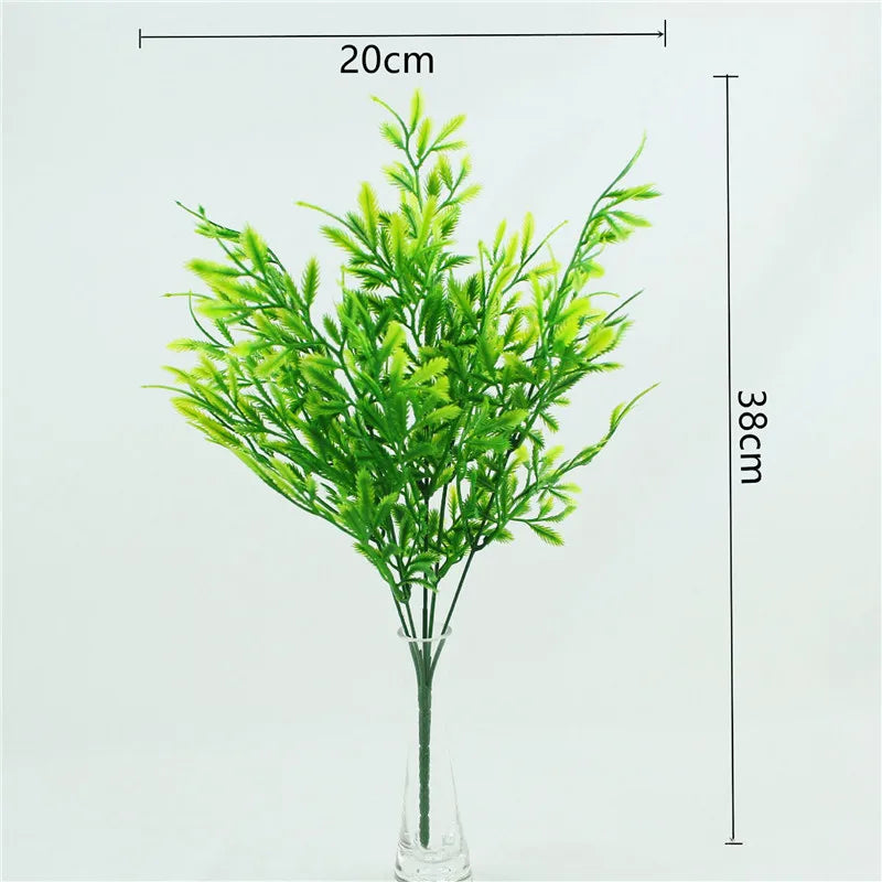 A tall artificial fern plant with bright green leaves displayed in a glass vase.