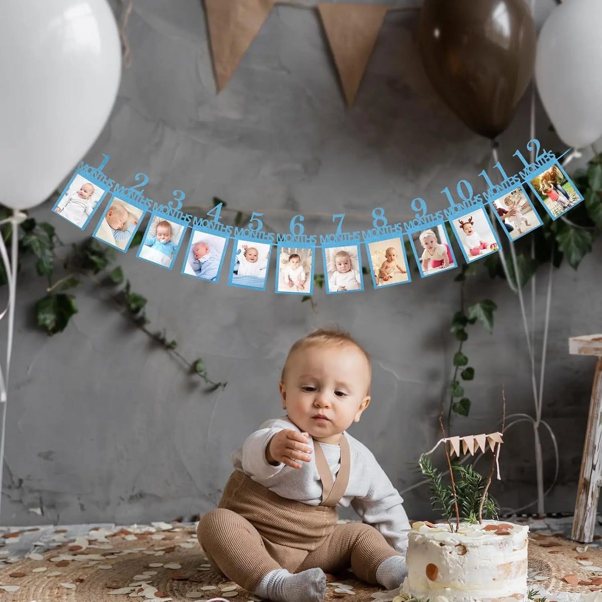 A baby sitting on a rug in front of a decorative banner marking months for a first birthday growth record.
