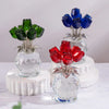A display of crystal rose decorative flowers in shades of green and blue on white pedestals.