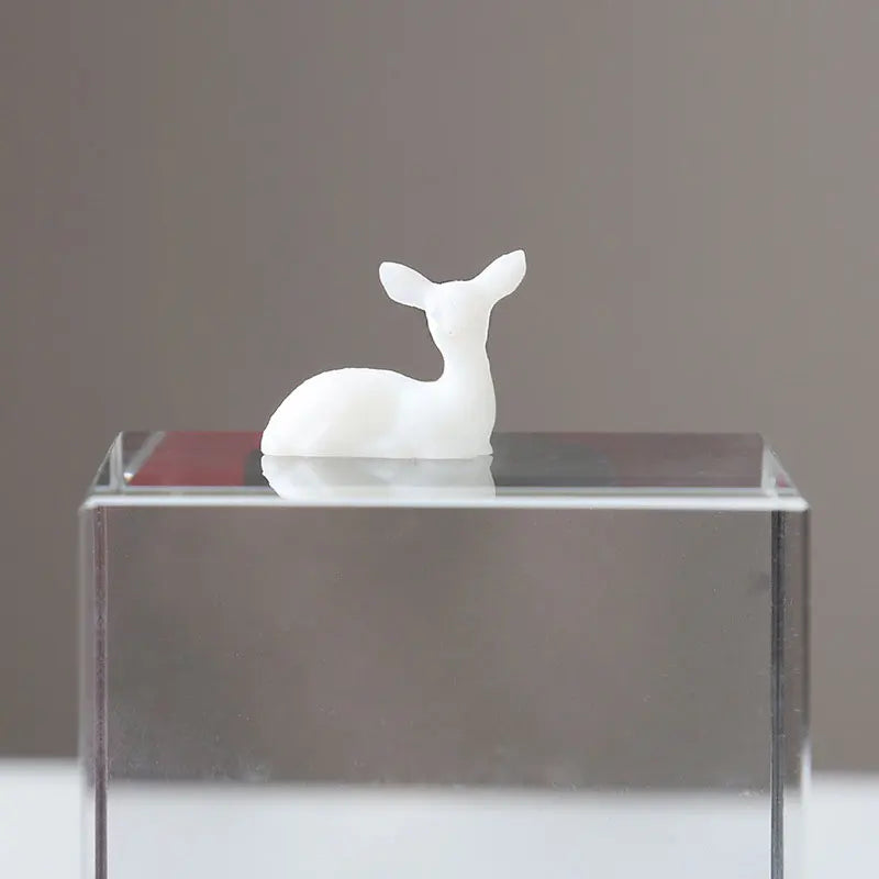 A white resin ornament of an elk or deer head is displayed on a clear glass block.