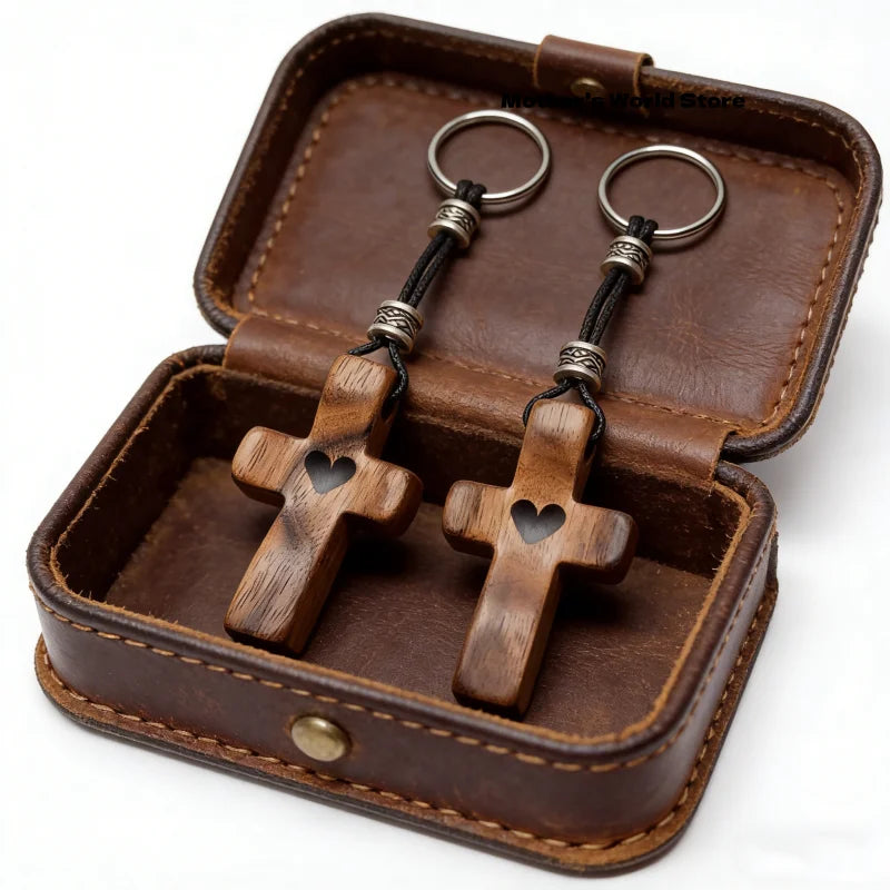 A handcrafted walnut cross keychain displayed inside a brown leather box.