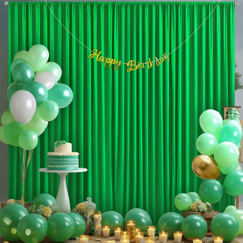 A vibrant green satin backdrop curtain decorated with balloons, a cake, and gold accents for a birthday party.