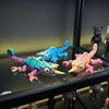 A collection of glow in the dark 3D printed chameleon fidget toys in various bright colors displayed on a glass shelf.