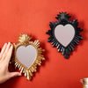Two heart-shaped wall pendants, one golden flame and one black, displayed against a red background.