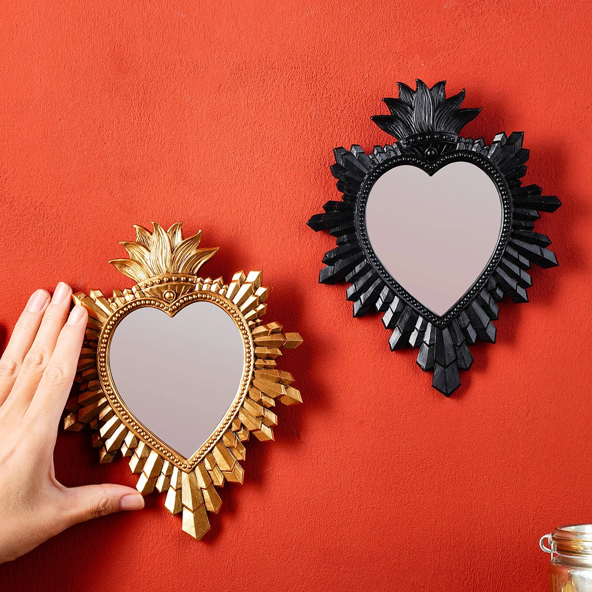 Two heart-shaped wall pendants, one golden flame and one black, displayed against a red background.