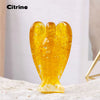 A natural Citrine crystal figurine shaped like a guardian angel, resting on a white surface.
