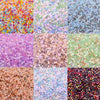 A grid of mixed colored faceted bicone glass beads for jewelry making in various shades of pink, purple, green, and blue.