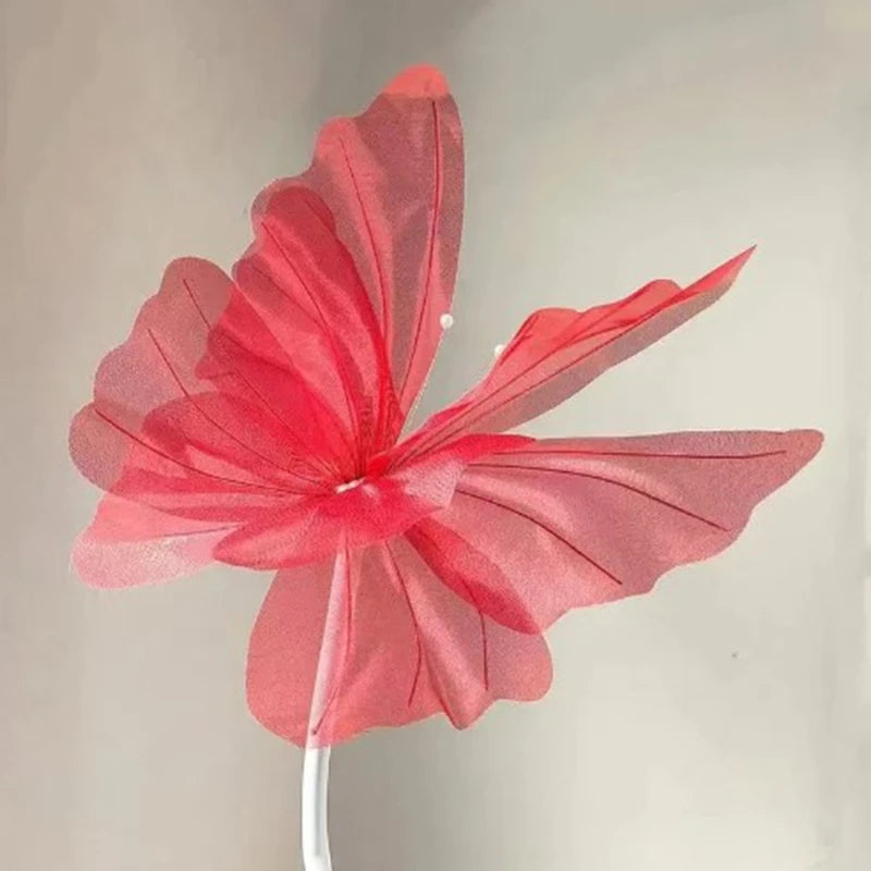 A vibrant pink silk artificial butterfly decoration with red accents, mounted on a white stick.