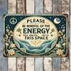A vintage metal wall sign with a dark teal background featuring a peace symbol, moon, and text reminding viewers to be mindfu