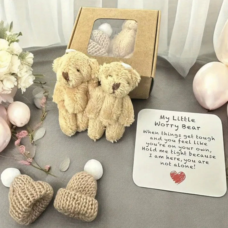 A fluffy beige teddy bear plush toy with an encouraging card and a cardboard gift box displayed on a gray surface.