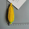 A bright yellow corn on the cob is positioned next to a ruler and a piece of paper.