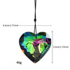A heart-shaped pendant made of iridescent, multicolored glass, suspended by a black cord.