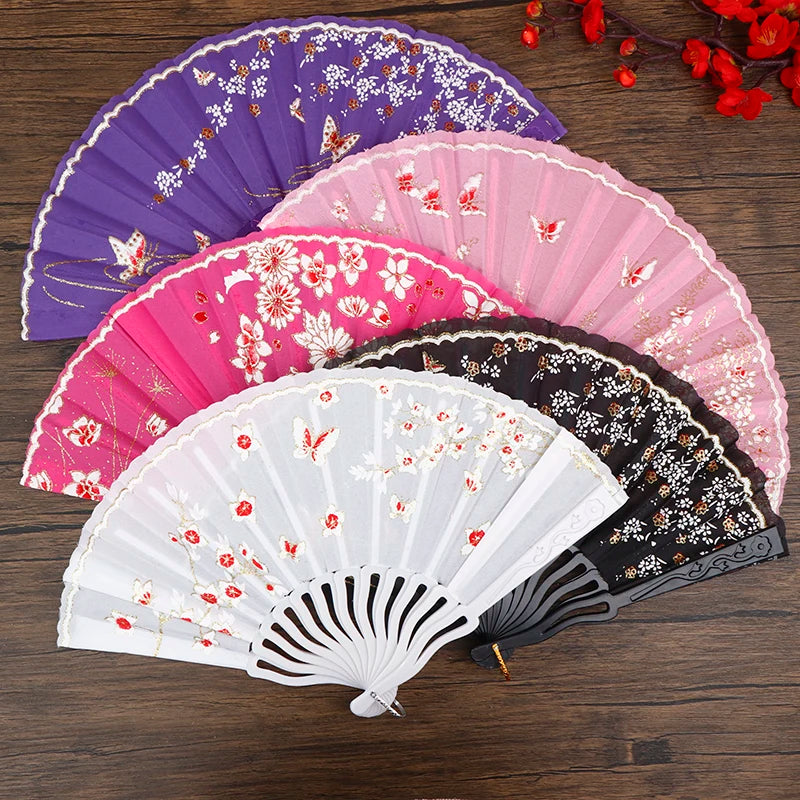 A collection of five folding fans in various shades of pink, purple, and white with floral patterns.