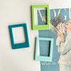 Three magnetic photo frames in shades of teal and lime green against a light background.