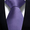 A purple silk necktie is tied and displayed against a black suit jacket.
