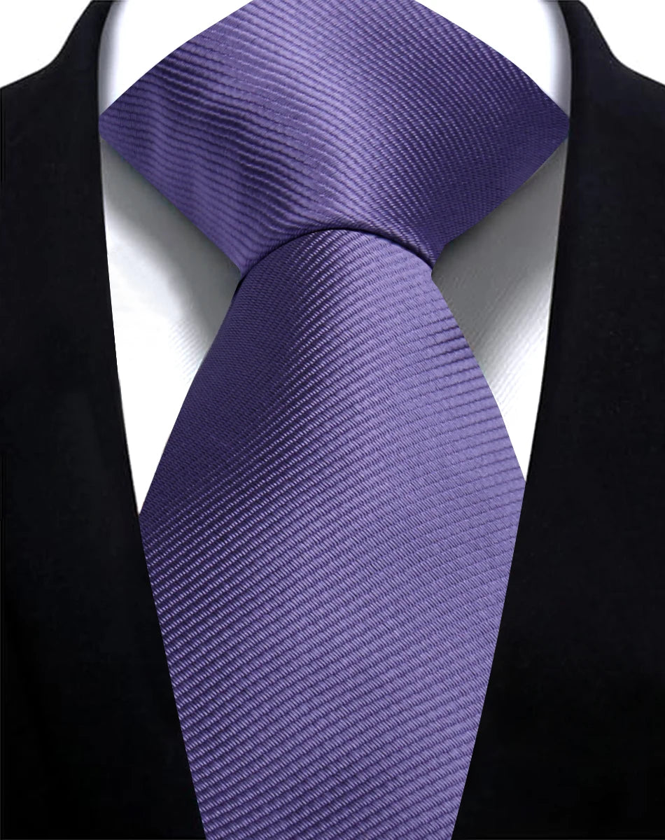 A purple silk necktie is tied and displayed against a black suit jacket.