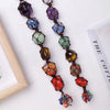 A string of natural crystal rolling stone pendants in various colors like purple, blue, green, and amber.