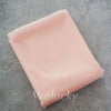 A square piece of light pink chiffon fabric is shown on a gray surface.